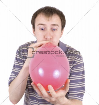 The young man inflates a red balloon