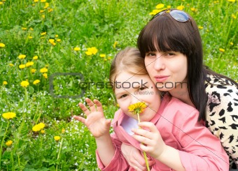 Mother and the daughter on a green meadow with dandelions