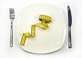 measuring tape on a dish. Symbol of dieting