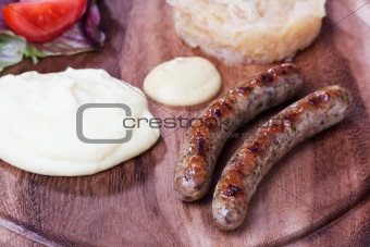 two bratwurst sausages on a wooden plate