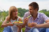 Young happy couple eating together outdoors