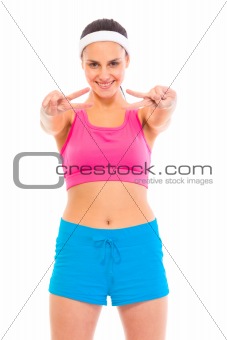 Smiling confident young  girl in sportswear showing victory gesture
