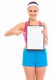 Smiling young fit girl pointing finger on blank clipboard
