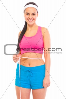 Smiling young girl with perfect sporty body measuring her waist
