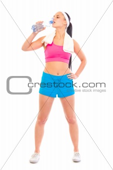 Fitness young girl with towel around neck drinking water from bottle
