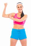 Cheerful fitness young girl in sportswear showing her muscles
