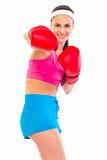 Cheerful fit young girl in boxing gloves punching
