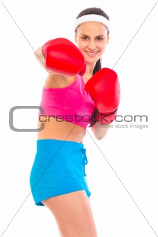 Cheerful fit young girl in boxing gloves punching
