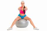 Smiling young girl doing exercises on fitness ball
