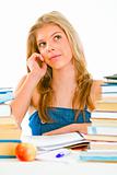 Teen girl sitting at table with books and dreamy looking in corner
