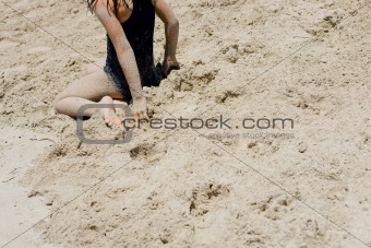 Young girl sits in sand