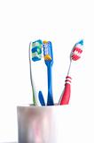 colorful toothbrushes in a glass over white