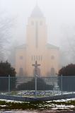 Church in the fog with stone cross and fence
