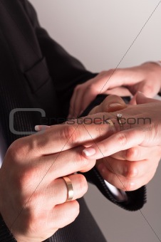 Groom putting a ring on bride's finger during wedding ceremony