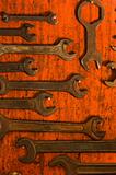 Many rusty spanners on wooden board