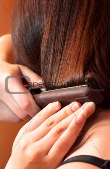 Girl using iron on her hair