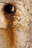Rusty hole in concrete wall