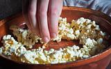 Hand taking out popcorn from brown dish