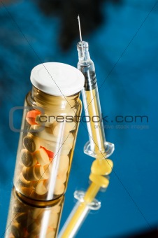Medicine bottle with sirynge on blue background with reflection