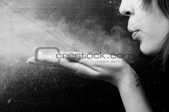 woman blowing white powder on black background