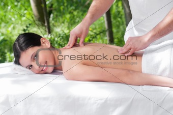 Happy young woman getting massage from a therapist