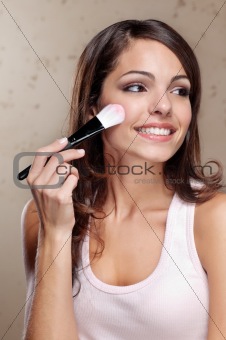 Young woman applying cosmetic paint brush