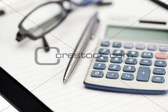 Note pad, pen, glasses and pocket calculator
