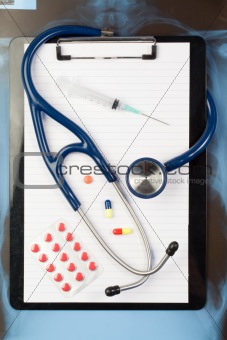 Note pad and blister strip with medicine and blue stethoscope
