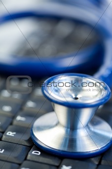 Blue stethoscope in the middle of keyboard