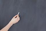 Hand holding a chalk and and ready to write on a blackboard