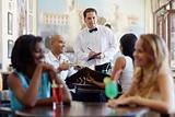 people ordering meal to waiter in restaurant