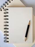 Light cream color paper note book and black pencil
