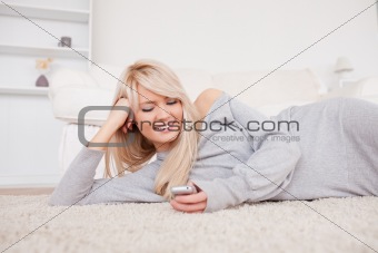 Attractive blond woman playing with cell phone lying down on a c