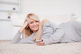Beautiful blond woman playing with cell phone lying down on a ca