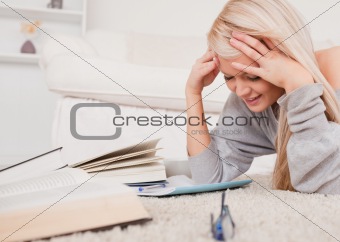 Attractive blond woman lying on a carpet being angry with her co