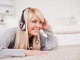Attractive blond woman with headphones lying on a carpet