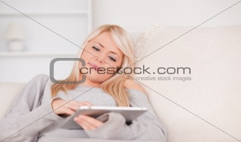 Beautiful blond woman lying on a sofa relaxing on a line of tabl