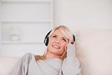 Pretty blond woman with headphones lying in a sofa