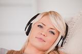 Beautiful happy blond woman with headphones lying in a sofa