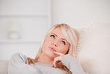 Portrait of a pensive blonde woman lying on a sofa