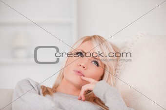Portrait of a pensive blonde woman lying on a sofa