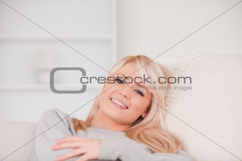 Smiling blonde woman lying on a sofa