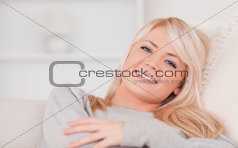 Portrait of a smiling blonde woman lying on a sofa