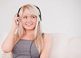 Beautiful young blond woman with headphones sitting in a sofa