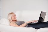 Beautiful woman relaxing on laptop lying on a sofa