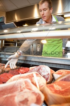 Market assistant picking meat