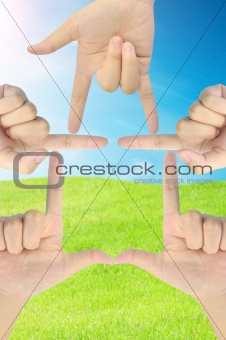 hand as home shape on fresh grass and blue sky