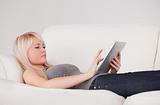 Pretty woman lying on a sofa relaxing on a line of tablet comput
