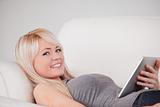 Charming woman lying on a sofa relaxing on a line of tablet comp