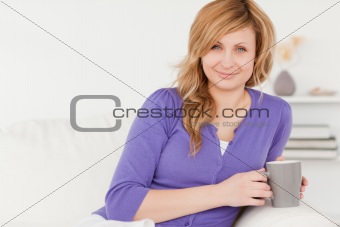 Beautiful red-haired woman holding a cup of coffee while sitting